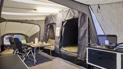 In the Camp-Let Passion there is a dining table and chairs. Both bedroom doors are open. The kitchen area is at the side.
