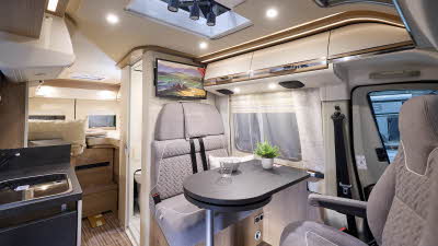 Malibu Van diversity GT skyview 640’s interior has beige upholstery.  The two rear seats have fitted seat belts.  There is a skylight above them which is open with three spotlights.  It has high level lighting.  There is a rear fixed bed.