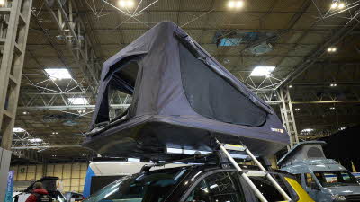 The TentBox GO is shown on a yellow jeep.  Its canvas is grey with black windows.  There is a silver ladder.
