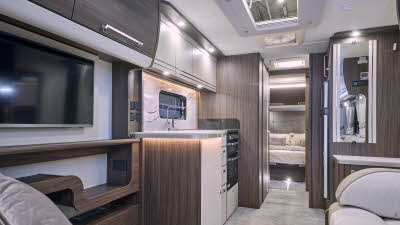 Buccaneer Barracuda’s interior has cream and beige upholstery with dark wooden furniture.  There is a L shaped sofa at the front with a large TV placed on the wall on the left.  There is a fixed island bed in the bedroom at the rear.