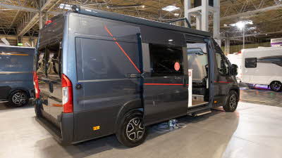 The Elddis Whirlwind GTV 563 is blue with red stripe decals, its sliding door is open.