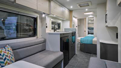 Xplore XC QUAD's interior has grey upholstery with pale wooden furniture.  Its kitchen is on the side with dark grey units.  There is a fixed island bed and the washroom is to the rear