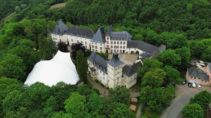  Drone photo Wiltz Castle surrounded by lush green trees Luxembourg