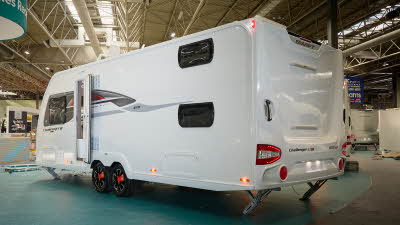 Swift Challenger Grande SE 670's exterior is white with grey and red graphics.  The caravan is a twin axle and has its corner steadies down.