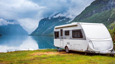 caravan sitting by a lake by mountains