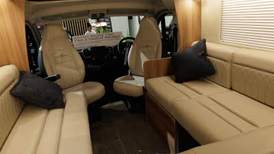 The Auto-Trail Frontier Comanche has cream leather upholstery and the two front seats are swivelled to join the lounge area.  There are two black cushions in the corners of the sofas.