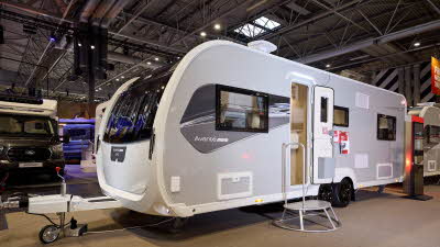 The Elddis Avanté APEX 840 has a grey exterior with a grey and black decal.  The entrance door is open and there is a metal step to gain easy access.