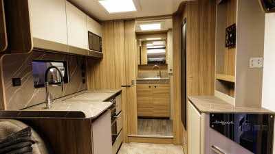 The Bailey Autograph 72-2 has large coffee and cream units with wooden surrounds.  The kitchen is on the left with a microwave in an overhead locker.  The washroom is at the rear and the basin and tap is in front of the mirror.