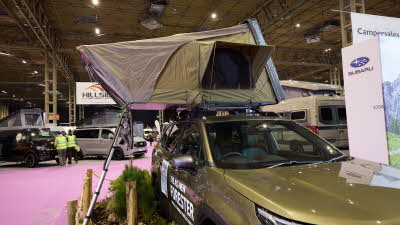 The ARB 4x4 Accessories Esperence is displayed on a green Subaru Forester.  It has khaki and cream canvas.  The window is open and there is a silver ladder to gain entry.