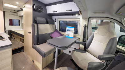 The Sun Living V Series 65SL has beige carpet and its upholstery is dark brown with cream inserts.  The cabinets are white and dark wood.  Towards the rear there is a fixed bed.