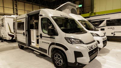The Benimar Benivan 144 is white with black and yellow decals. Its sliding door is open.