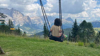 Child on swing with a scenic view of the Dolomites