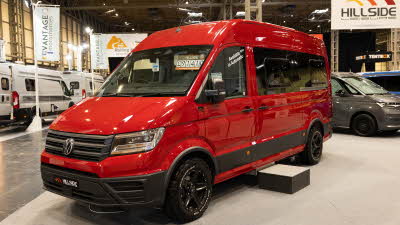 The Hillside Leisure Hopton 600RL is red, its sliding door is closed and there is a step beside it.