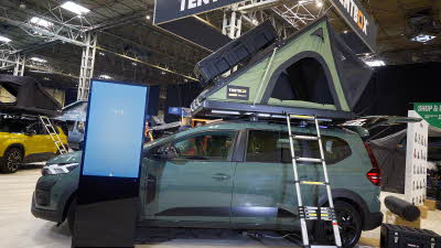 TentBox Cargo 2.0 is shown on a Dacia.  The canvas is green and it has a black hard top with a storage box.  There is a silver ladder to gain access.