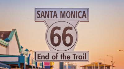 A sign under a sunset sky saying Santa Monica 66 End of the Trail