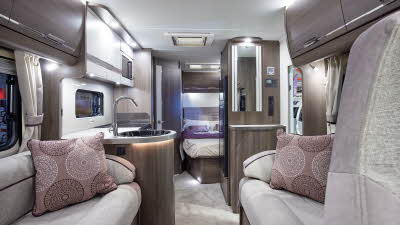 Coachbuilt interior, grey upholstery, pink cushions, wooden furniture, cream carpet