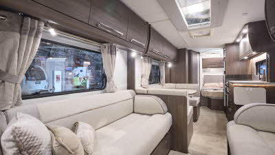 Buccaneer Aruba interior, it is cream with dark wood furniture.  There is a dinette opposite the kitchen unit.  The fixed French bed is just beyond this and there are large skylights.  