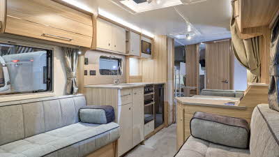 Bailey Pegasus Grande GT75 Ancona’s interior has pale wooden furniture with grey upholstery.  The kitchen is in the middle with a bedroom with a ladder to the bunk beds at the rear.  There is a roof light above the kitchen.