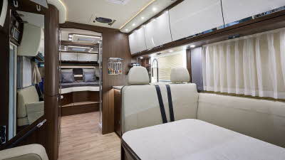 MORELO PALACE 85L’s interior has cream leather upholstery.  Its furniture is dark wood with white doors.  The two rear seats have seatbelts.  At the rear there is a large fixed bed.  