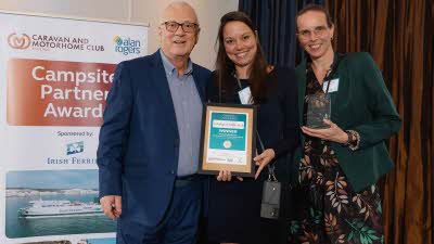 A Caravan and Motorhome Overseas Campsites Award Winner with the Chairman next to a sign showing Campsite Partner Awards, with Irish Ferries below it