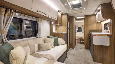 Interior of the Buccaneer Skyliner Bermuda with cream sofas edged with suede effect material. The rear bedroom door is open revealing the fixed island bed.  The large roof light will let natural light flood in.