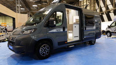 The Ace Motorhomes 1200 GL is dark grey.  Its sliding door and skylight are open.  Its number plate is blue.