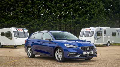 Blue Seat Leon Estate parked in front of two caravans