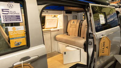 The Wildtracks Campervans Explorer has leather upholstery with cream cabinets.  The door to the toilet cabinet is open.