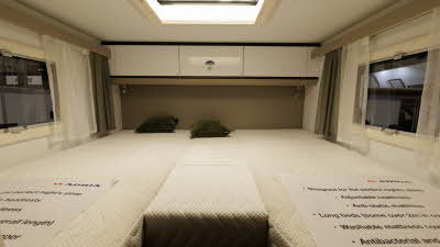 The Adria Compact Supreme DL has a rear fixed bed with white over head lockers and a window either side.  