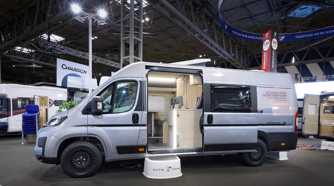 The Auto-Trail Expedition 68 is silver with black decals.  There is a white step by the open sliding door which reveals the interior.  