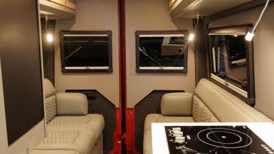 The Hillside Leisure Hopton 600RL has cream upholstery.  There are mid brown cabinets.  The kitchen hob is in the right hand corner.  The spot lights under the overhead cabinets are switched on. 