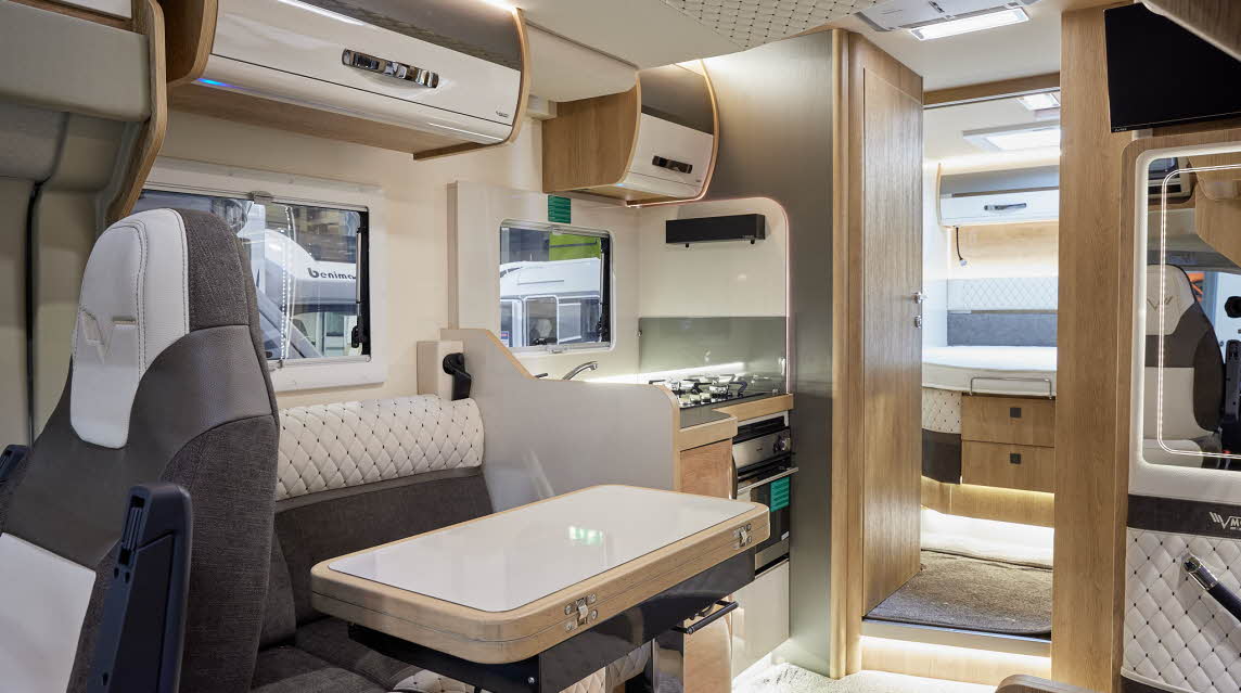 Mobilvetta Tekno Line Kea 90 has two tone black and cream embossed upholstery.  There are two tone overhead lockers. The floor has a cream carpet.  Towards the rear of the vehicle there is a step leading to the bedroom.  