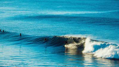 Blue sea with surfers enjoying a big wave of white 