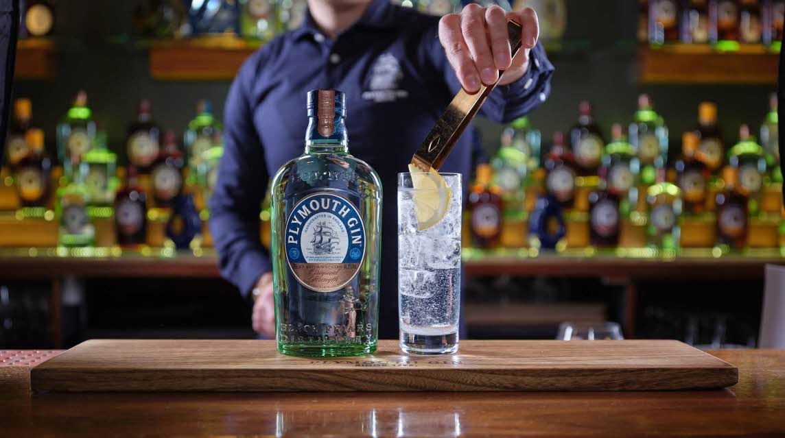 Bartender making a gin and tonic with a slice of lemon and plenty of ice