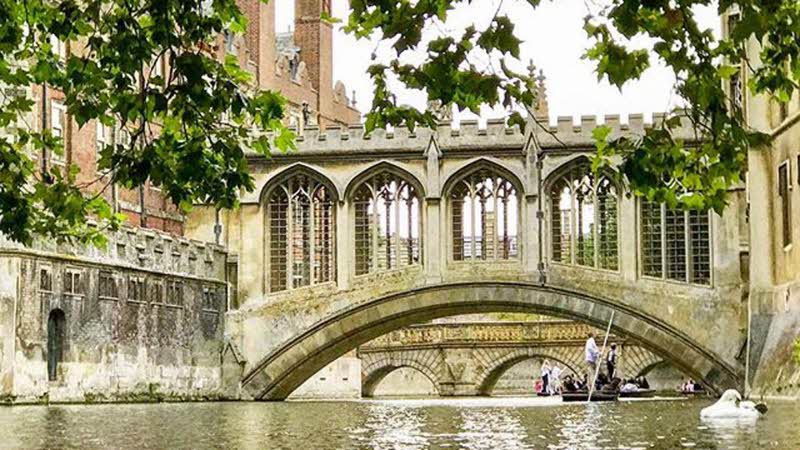 Punt on the River Cam passing under an ornate covered bridge