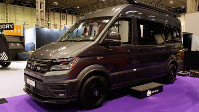The Bespoke Leisure Bespoke Edition Volkswagen Crafter has metallic paint, its sliding door is closed and there is a step in front of it to gain easy access.