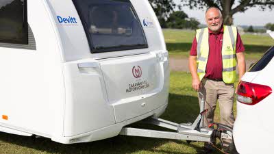 Man in high vis stood next to caravan a frame