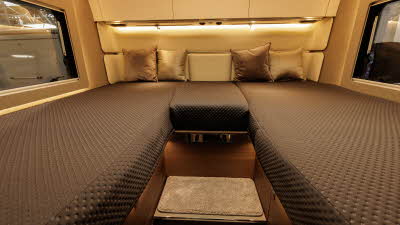 The Adria Supersonic 780 DL has a rear fixed bed.  There are two large windows either side of the bed.  There are four cushions on the bed and there are three cream overhead lockers.  In the front there are two steps to gain entry to the bed.