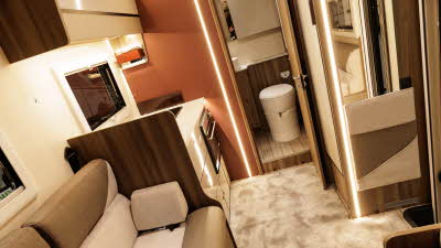 The Roller Team Kronos Compact 590 has coffee and cream upholstery.  The kitchen is towards the rear and through the open door, there is an end washroom.  