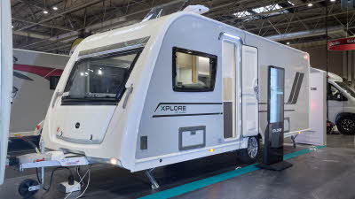 Xplore XC QUAD's exterior is white with black/turquoise decals.  It has large windows.  The roof light is open.  There is an interactive display on the right