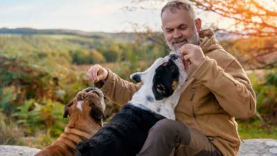 man giving his two dogs treats