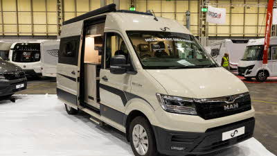 The Mega Mobil Mega Classic 600 S Hubbett is cream with black decals.  Its sliding door is open.