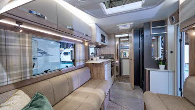Swift Challenger Exclusive 650's interior has pale wooden furniture with beige upholstery.  The washroom is in the centre of the caravan with the bedroom at the rear.