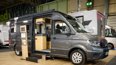 Adria Twin Max’s exterior is dark grey, the sliding door is open and there are wooden steps to gain easy access.  There is an interactive information board by the side of the van.