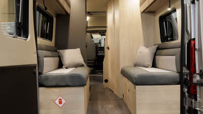 The Auto-Trail Expedition 67 has beige and cream upholstery with pale wood furniture, the rear lounge has two sofas with a cream cushion on each.