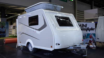 Trigano Mini Freestyle 270's exterior is white with a grey stripe decal.  Its pop top roof is extended