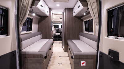 Benimar Benivan 122 has brown and cream upholstery with matching cabinets.  The rear doors are open revealing the rear lounge.