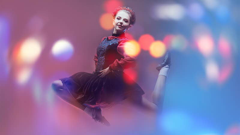 Beautiful professional dancer woman in national Irish costume makes a high jump during the dance. Studio full-length portrait. Traditional Irish dances.