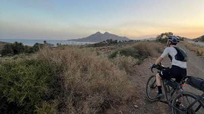 a cyclist takes a break as the sun sets over the Spanish coast