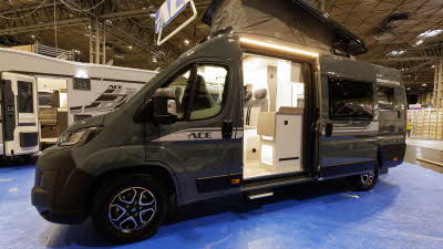The Ace Motorhomes 1200 SLT is grey with a white decal, its rising roof and sliding door are open.
